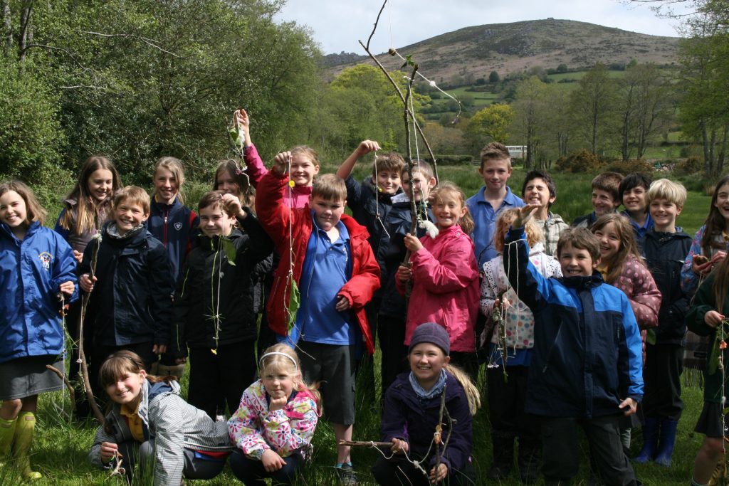 Children hold up their creations of items they have found on a walk